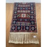 A SMALL VINTAGE TUNISIAN RED AND BLUE PATTERNED FRINGED RUG