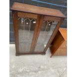 AN OAK 'NEW PLAN' GLAZED AND LEADED TWO DOOR DISPLAY CABINET
