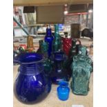 A QUANTITY OF COLOURED GLASS MAINLY BOTTLES BUT TO INCLUDE JUGS