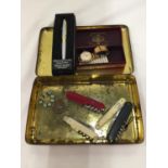 A VINTAGE TIN CONTAINING PEN KNIVES INCLUDING AN ORIGINAL SWISS ARMY KNIFE, WILKINSON SWORD, ETC