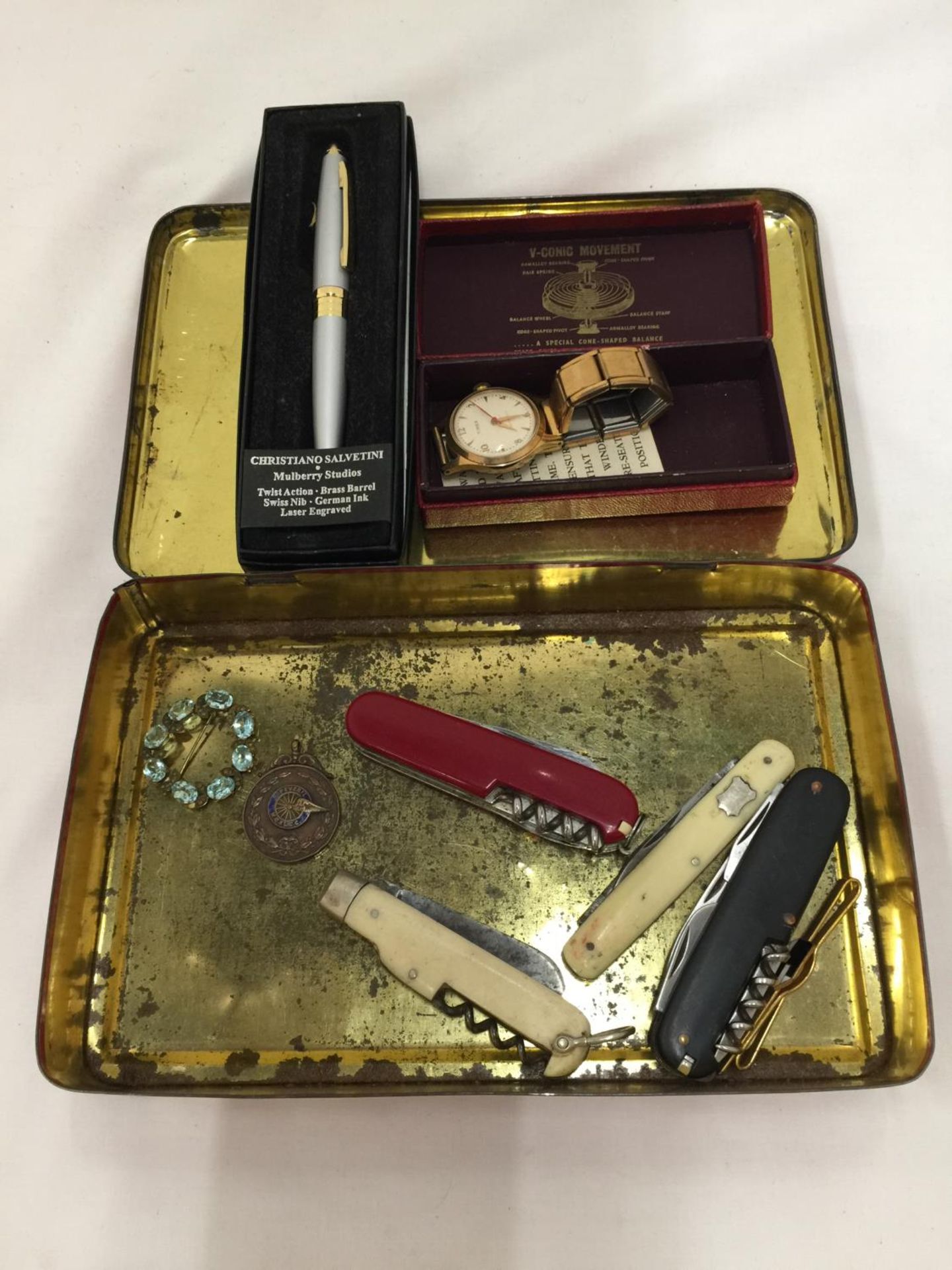 A VINTAGE TIN CONTAINING PEN KNIVES INCLUDING AN ORIGINAL SWISS ARMY KNIFE, WILKINSON SWORD, ETC