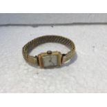 AN 18CT GOLD CASED LADIES WATCH ON A ROLLED GOLD BRACELET