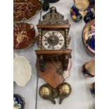 A WOODEN CASED WALL CLOCK WITH BRASS COLUMN DESIGN, BRASS FIGURE WORK, TOPPED WITH ATLAS,