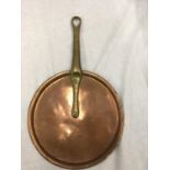 A VINTAGE COPPER SKILLET WITH A BRASS HANDLE