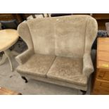 A MODERN WINGED TWO SEATER COTTAGE SETTEE ON FRONT CABRIOLE LEGS