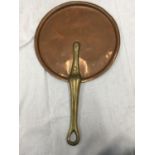 A VINTAGE COPPER SKILLET WITH A BRASS HANDLE