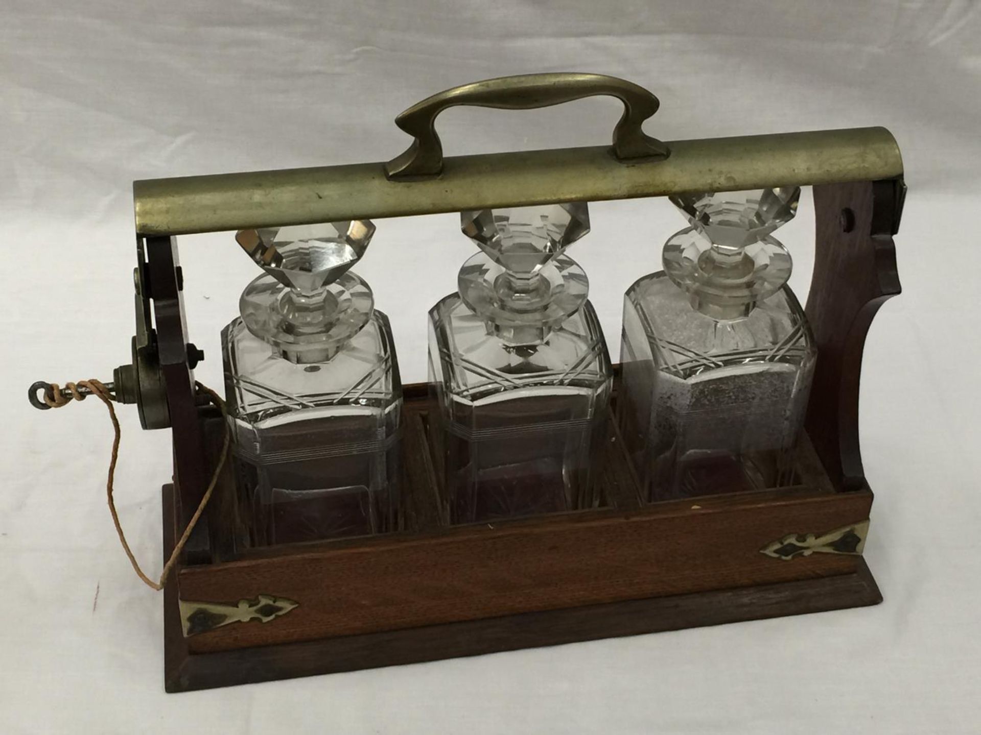 A VINTAGE MAHOGANY AND BRASS TANTALUS WITH THREE MATCHING DECANTERS AND KEY - Image 3 of 16