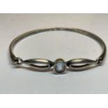 A SILVER BANGLE WITH A LIGHT BLUE STONE IN A PRESENTATION BOX