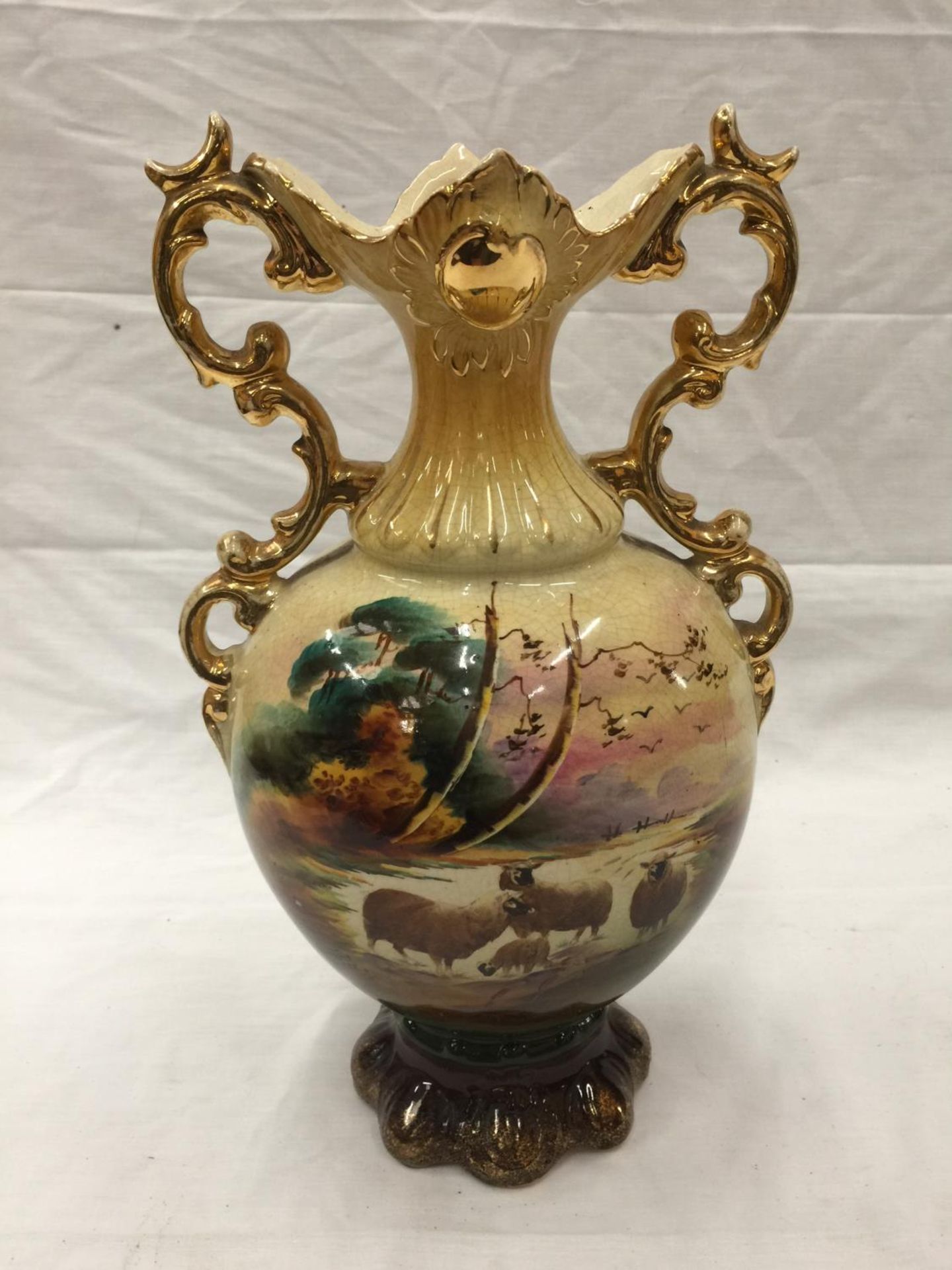 A VINTAGE HAND PAINTED URN WITH GILT DETAILING AND INDISTINCT SIGNATURE TO ART ON FRONT AND RAISED