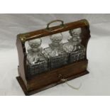 A VINTAGE MAHOGANY TANTALUS DECANTER SET WITH BRASS DETAILING AND A KEY