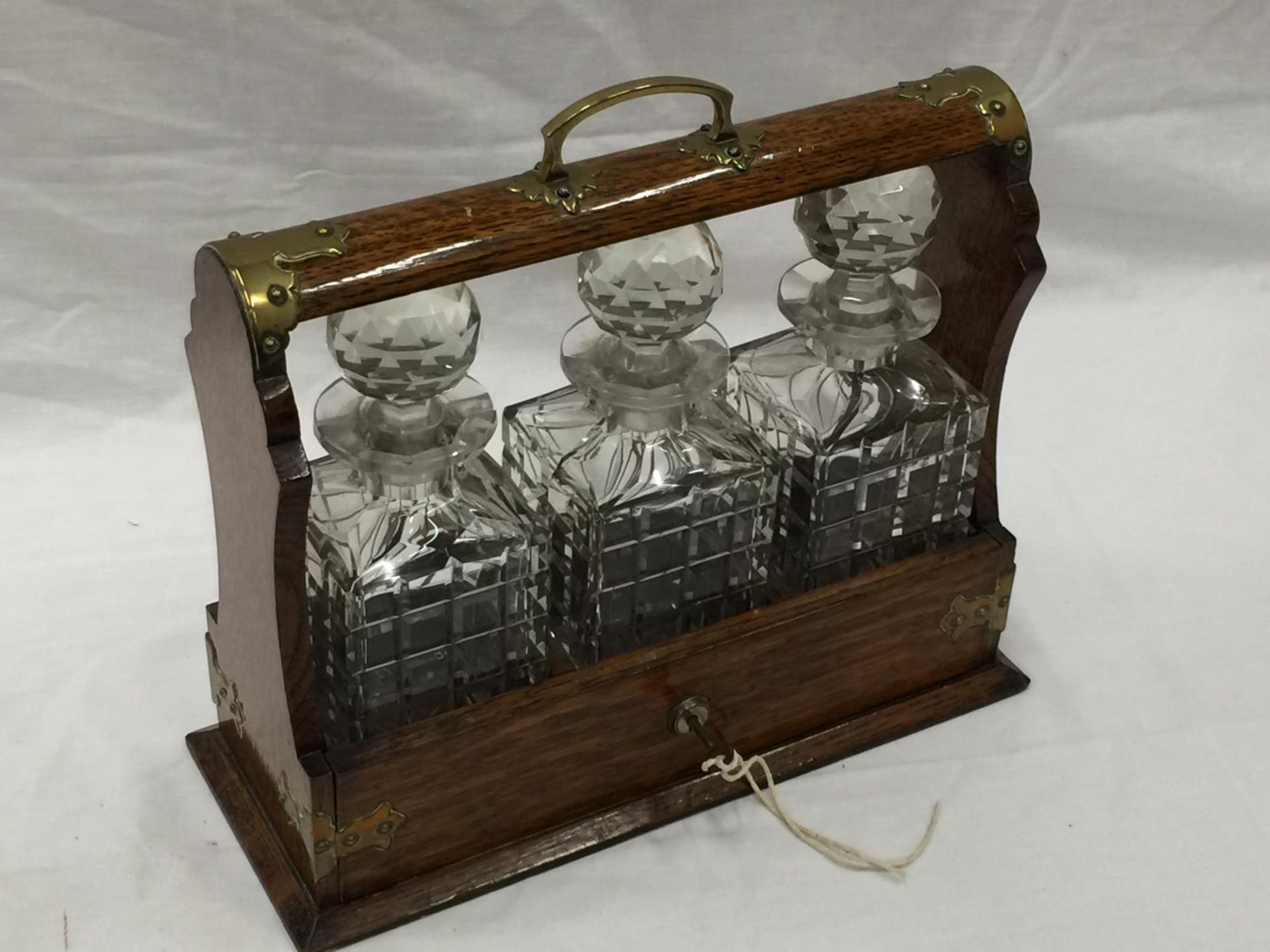 A VINTAGE MAHOGANY TANTALUS DECANTER SET WITH BRASS DETAILING AND A KEY