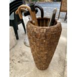 A WICKER STYLE BASKET AND AN ASSORTMENT OF WALKING STICKS