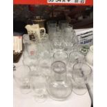A LARGE QUANTITY OF GLASSES TO INCLUDE HANDLED PINT GLASSES, WINE, A WATER CARAFE AND TUMBLER,