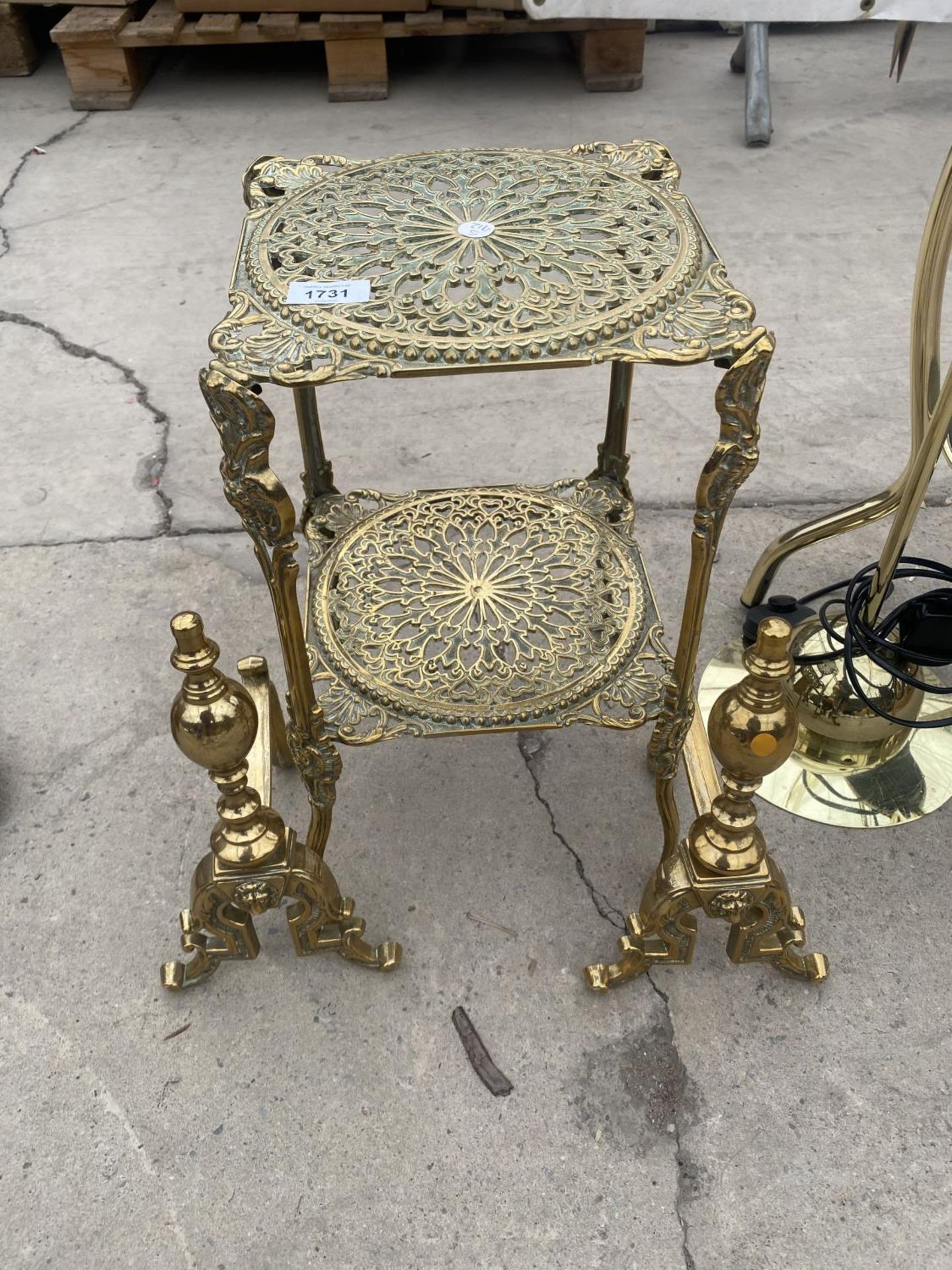 A DECORATIVE BRASS TWO TIER STAND AND A PAIR OF BRASS FIRE DOGS