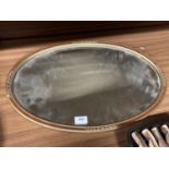 A VINTAGE OVAL MIRROR WITH BEVELLED GLASS 56CM X 36CM