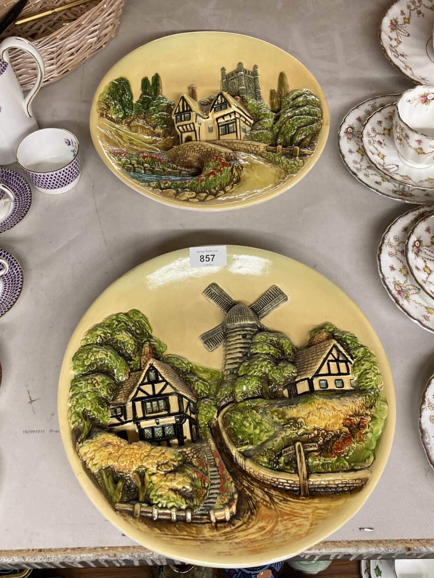 TWO CERAMIC 3-D WALL PLAQUES WITH SCENES OF RURAL VILLAGES