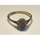 A 9 CARAT GOLD RING WITH A CENTRE RUBY SURROUNDED BY DIAMONDS SIZE O