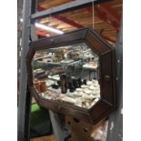 AN ARTS AND CRAFTS STYLE VINTAGE WALL MIRROR IN AN OCTAGONAL SHAPE WITHBEVELLED GLASS AND MAHOGANY