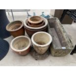 A RECONSTITUTED STONE TROUGH AND AN ASSORTMENT OF GLAZED POTS