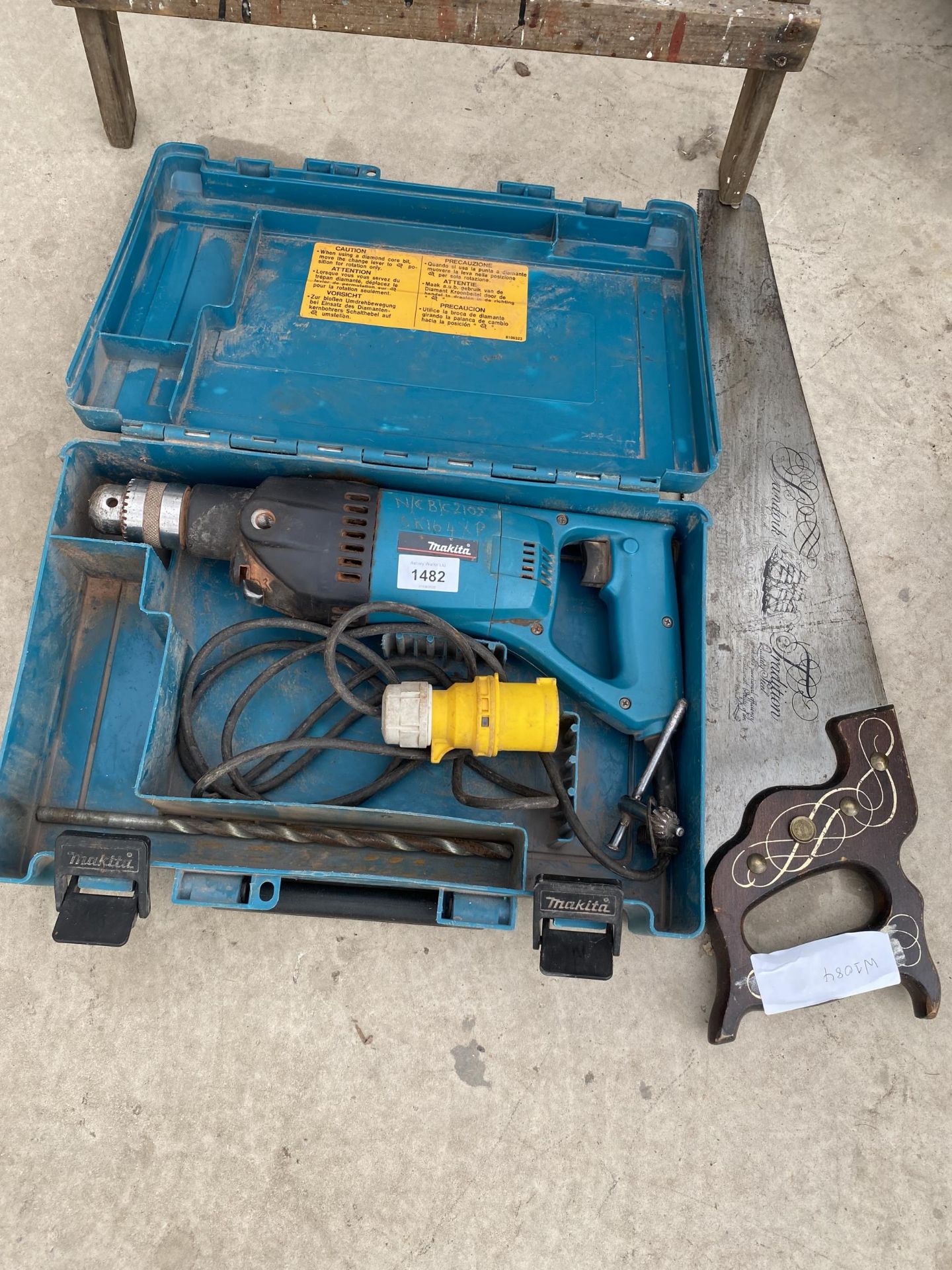A MAKITA 110V DRILL AND A VINTAGE HAND SAW