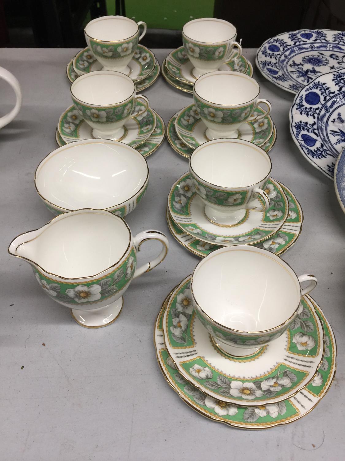 A CHINA TEASET IN A GREEN AND WHITE FLORAL PATTERN TO INCLUDE CUPS, SAUCERS, SIDE PLATES, CREAM