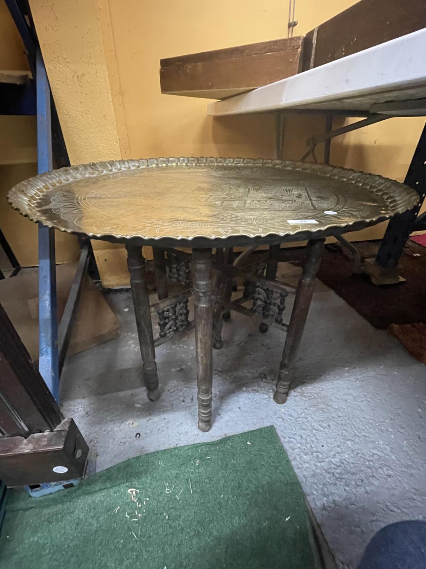 A LARGE SIX LEGGED FOLDING TABLE WITH BRASS TOP DEPICTING EGYPTIAN LIFE DIAMETER 73CM