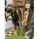 A BRASS UMBRELLA/STICK STAND WITH COAT OF ARMS TO THE FRONT TO INCLUDE WALKING STICKS AND UMBRELLAS