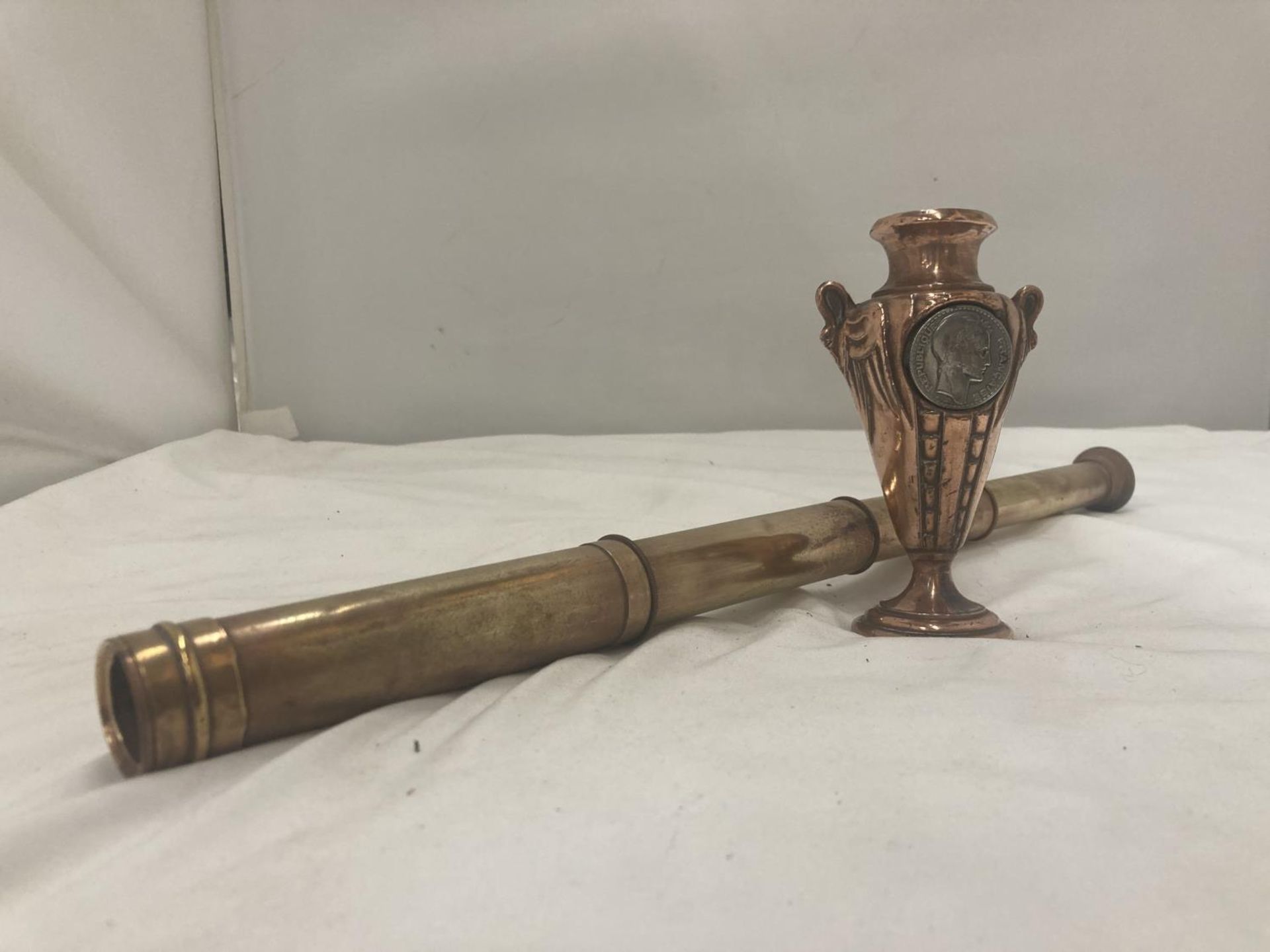 A THREE DRAWER VINTAGE BRASS TELECOPE AND A SMALL COPPER URN STYLE VASE WITH INLAID SILVER COIN