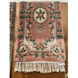 A SMALL PINK PATTERNED FRINGED RUG