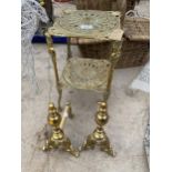 A DECORATIVE BRASS TWO TIER STAND AND A PAIR OF BRASS FIRE DOGS