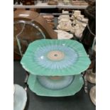 A SHELLEY ART DECO CAKE STAND WITH CHROME HANDLE IN A GREEN AND BLUE PATTERN