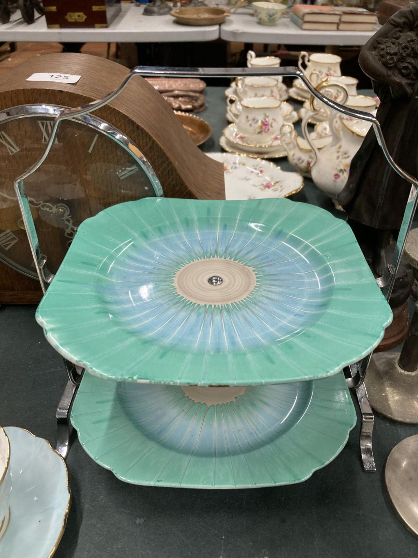 A SHELLEY ART DECO CAKE STAND WITH CHROME HANDLE IN A GREEN AND BLUE PATTERN