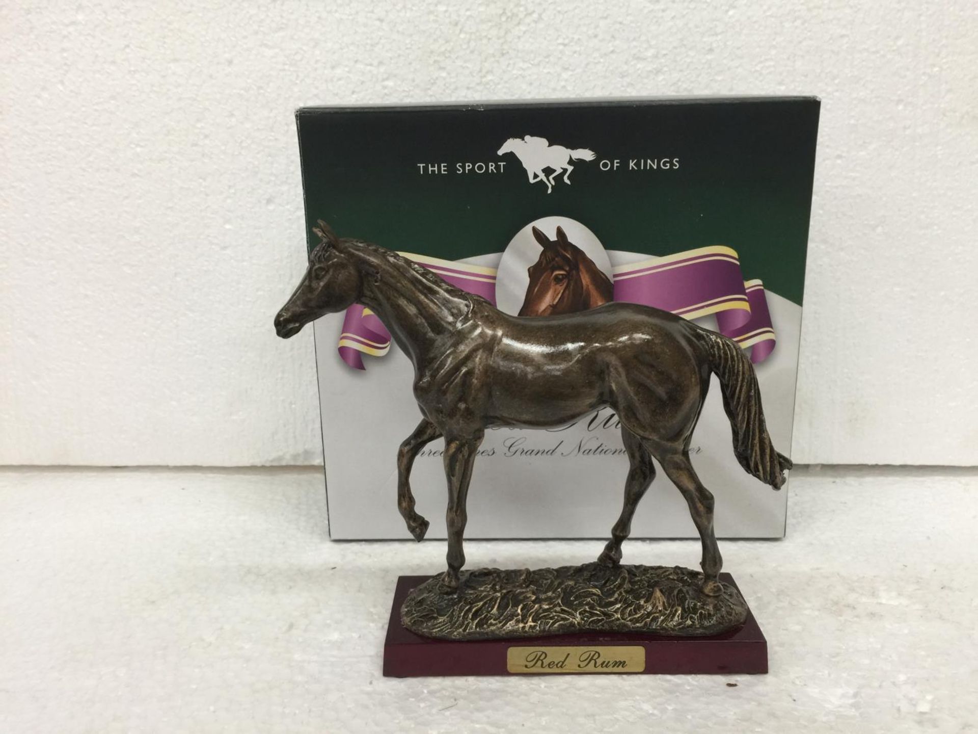 A BOXED RESIN SCULPTURE OF RED RUM RACE HORSE ON WOODEN PLINTH