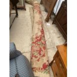 A LARGE CREAM AND RED PATTERNED FRINGED RUG