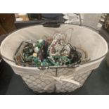 A WIRE BASKET CONTAINING A LARGE QUANTITY OF COSTUME JEWELLERY TO INCLUDE BEADS, NECKLACES, BANGLES,