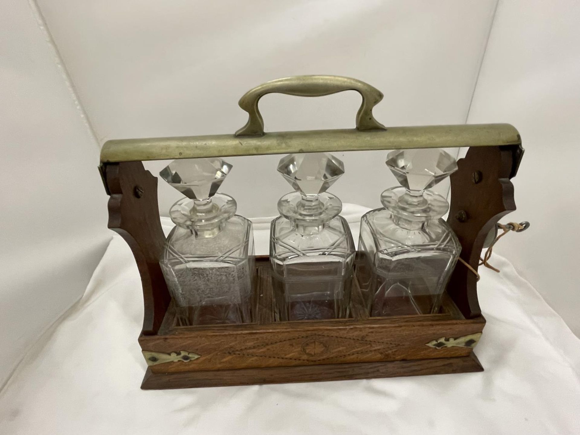 A VINTAGE MAHOGANY AND BRASS TANTALUS WITH THREE MATCHING DECANTERS AND KEY - Image 3 of 4