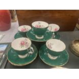 FIVE ADDERLEY CHINA CUPS AND SIX SAUCERS IN A DARK GREEN WITH A FLORAL PATTERN