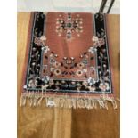 A SMALL PINK AND BLUE PATTERNED FRINGED RUG