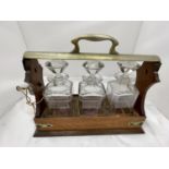 A VINTAGE MAHOGANY AND BRASS TANTALUS WITH THREE MATCHING DECANTERS AND KEY