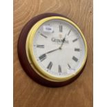 A WOODEN FRAMED BRASS WALL CLOCK BEARING THE NAME 'GUINNESS'