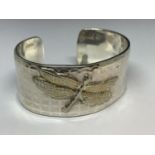 A WHITE METAL BANGLE WITH A YELLOW METAL DRAGONFLY DESIGN MARKED 925 750