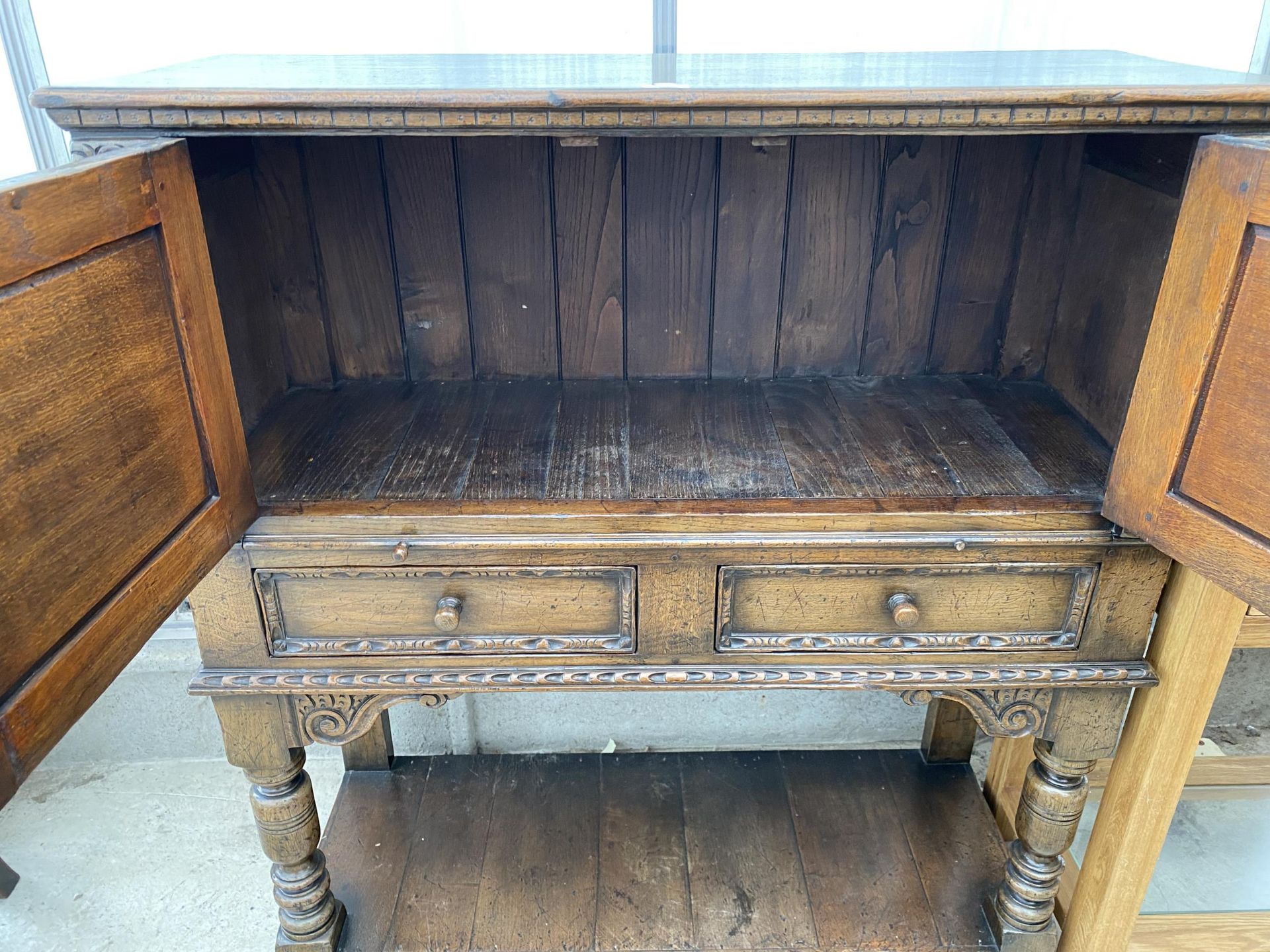 AN OAK JACOBEAN STYLE COCKTAIL CABINET WITH PANELLED DOOR, PULL OUT SLIDE, TWO DRAWERS AND A POT - Image 6 of 7