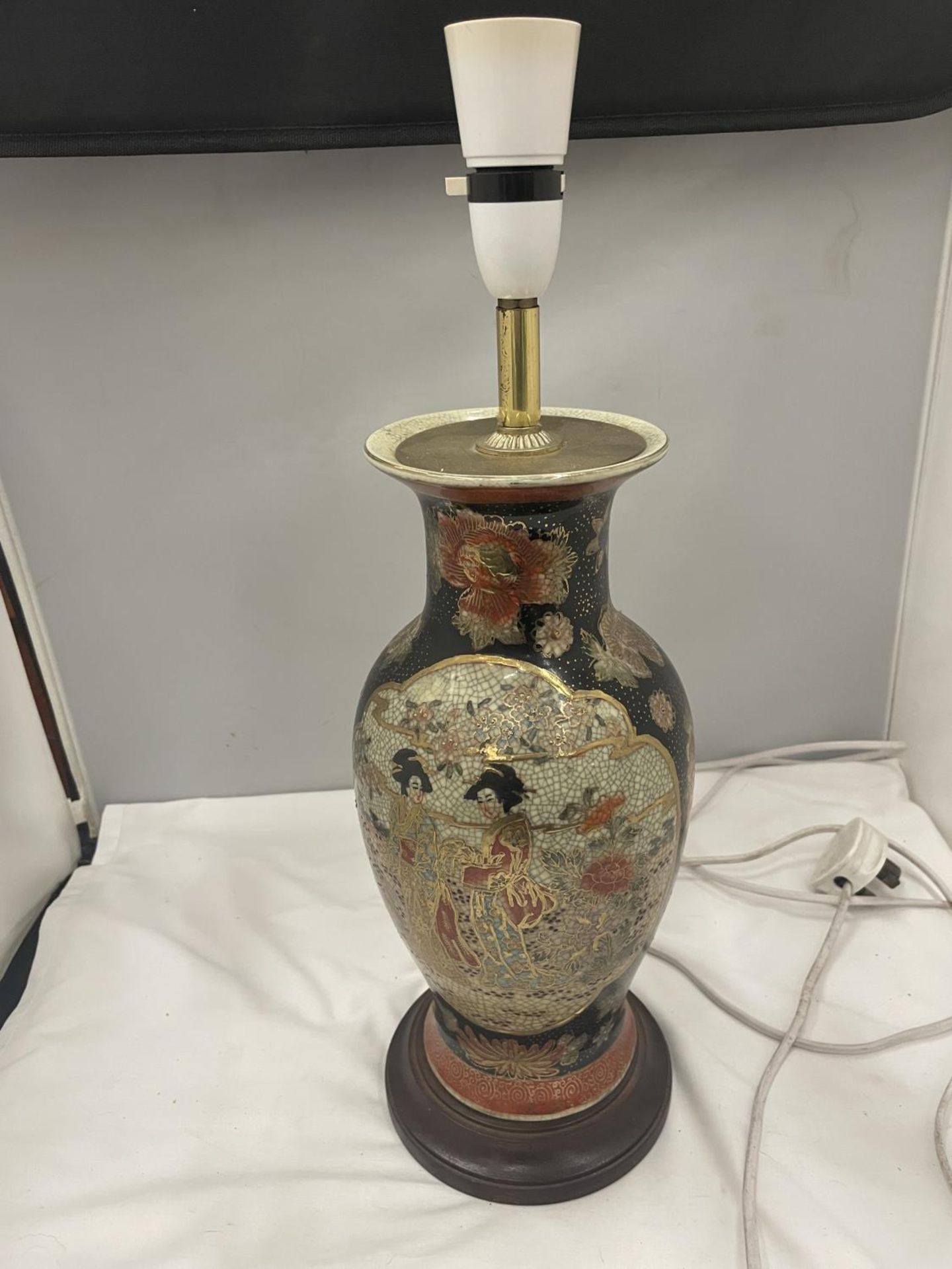AN ORIENTAL LAMP WITH BRASS DETAIL ON A WOODEN BASE