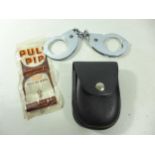 A PAIR OF HANDCUFFS, KEY AND POUCH