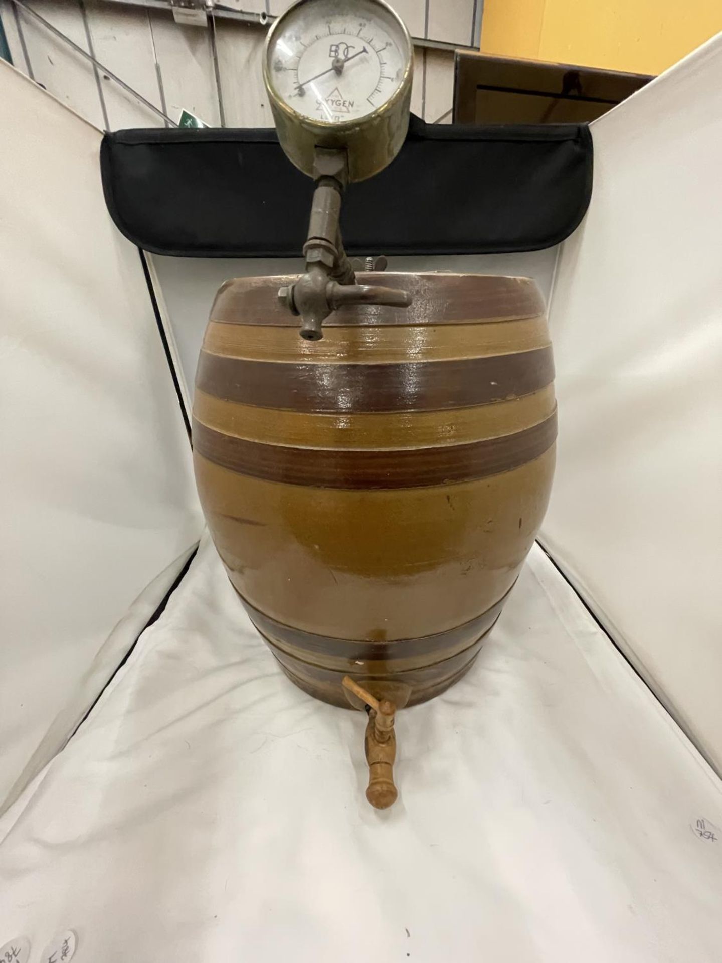 A LARGE STONEWARE BARREL WITH A WOODEN TAP AND A BOC GAUGE HEIGHT