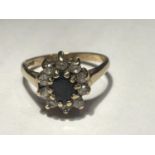 A 9 CARAT GOLD RING WITH A CENTRE SAPPHIRE SURROUNDED BY CLEAR STONES SIZE I