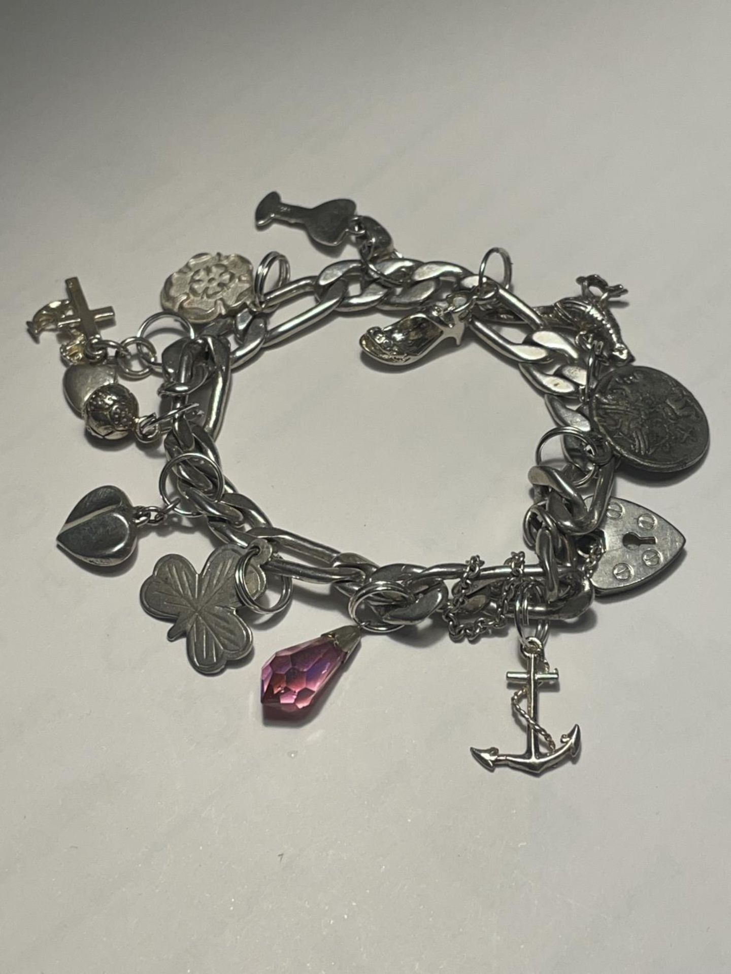 A SILVER CHARM BRACELET WITH HEART PADLOCK AND ELEVEN CHARMS