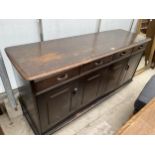 AN ERCOL STYLE SIDEBOARD WITH TWO BI FOLD DOORS AND FOUR DRAWERS 62" WIDE