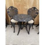 A CAST ALLOY BISTRO SET COMPRISING OF A ROUND FLORAL TABLE AND TWO CHAIRS WITH CUSHIONS