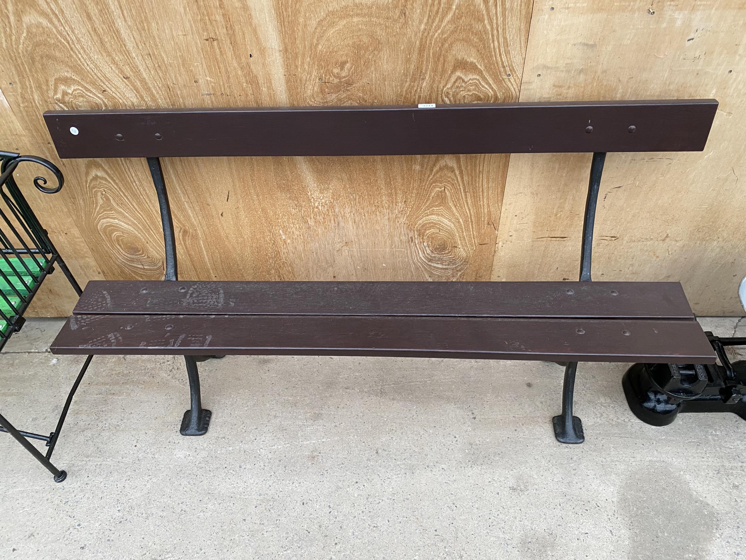 A WOODEN PLANK BENCH WITH CAST IRON LEG SUPPORTS